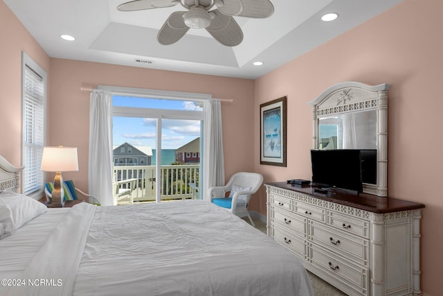 bedroom featuring ceiling fan, access to exterior, and a raised ceiling