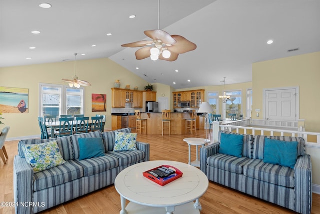 living room featuring light hardwood / wood-style floors, vaulted ceiling, and ceiling fan with notable chandelier