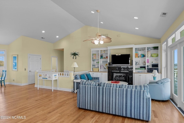 living room with light hardwood / wood-style flooring, ceiling fan, a fireplace, and vaulted ceiling