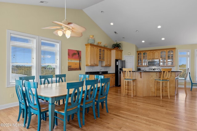 dining room featuring ceiling fan, sink, light wood-type flooring, and high vaulted ceiling