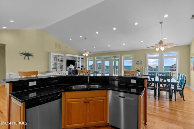 kitchen with dark stone countertops, dishwasher, and a center island with sink