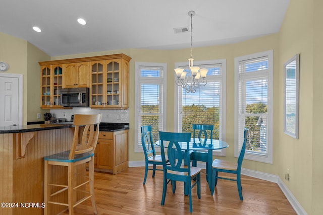 dining room featuring a healthy amount of sunlight, a chandelier, and light hardwood / wood-style flooring