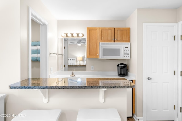 kitchen featuring a breakfast bar, dark stone countertops, and kitchen peninsula