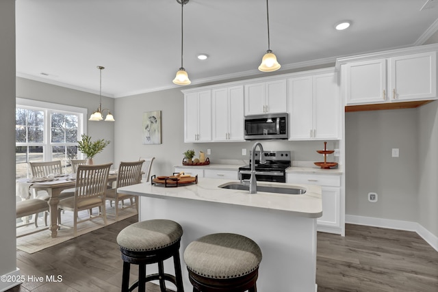 kitchen with stainless steel appliances, white cabinets, hanging light fixtures, and an island with sink