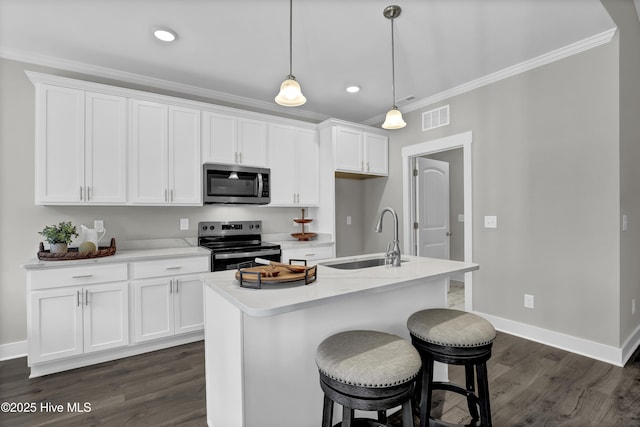 kitchen with hanging light fixtures, stainless steel appliances, a center island with sink, white cabinetry, and sink