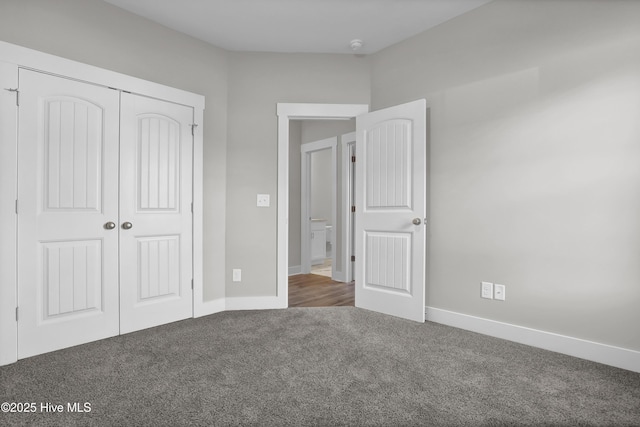 unfurnished bedroom with dark colored carpet and a closet