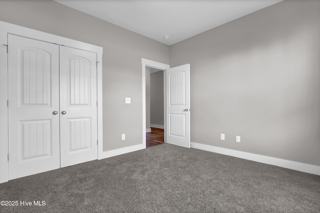 unfurnished bedroom with a closet and dark colored carpet