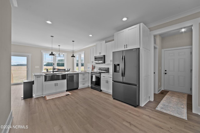 kitchen with pendant lighting, a healthy amount of sunlight, white cabinetry, and stainless steel appliances