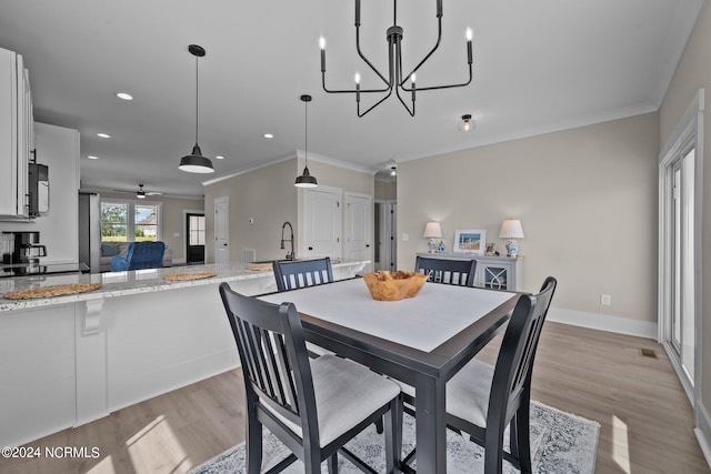 dining space with crown molding, light hardwood / wood-style flooring, and ceiling fan with notable chandelier