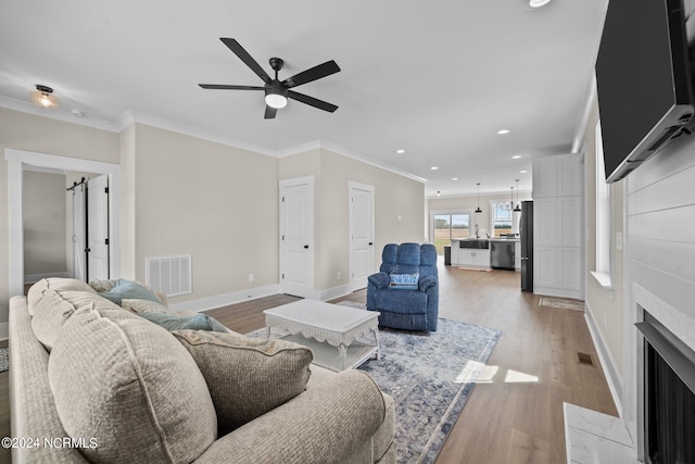 living room featuring ceiling fan, crown molding, and light hardwood / wood-style flooring