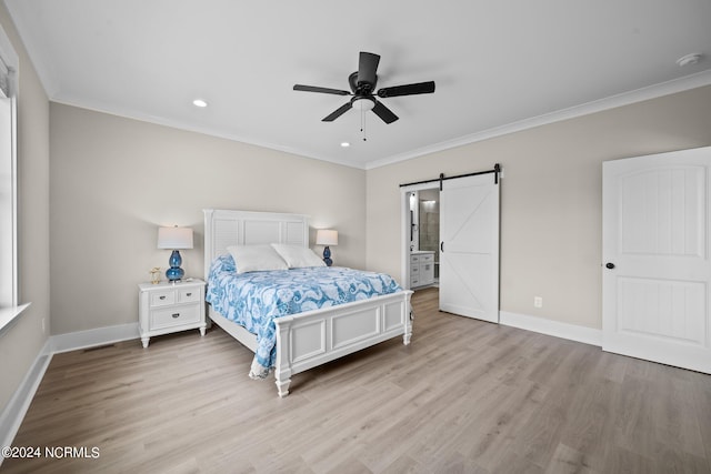 bedroom with crown molding, ensuite bath, light hardwood / wood-style flooring, ceiling fan, and a barn door