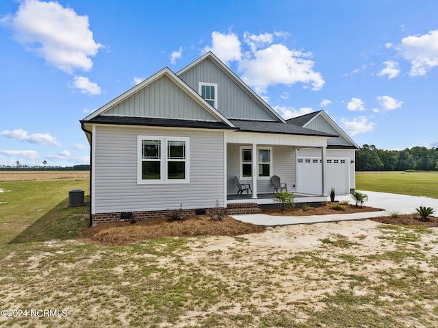 view of front of house featuring a porch, a garage, central AC unit, and a front lawn