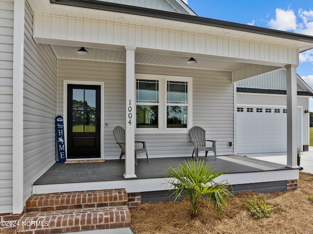 view of exterior entry with a porch and a garage