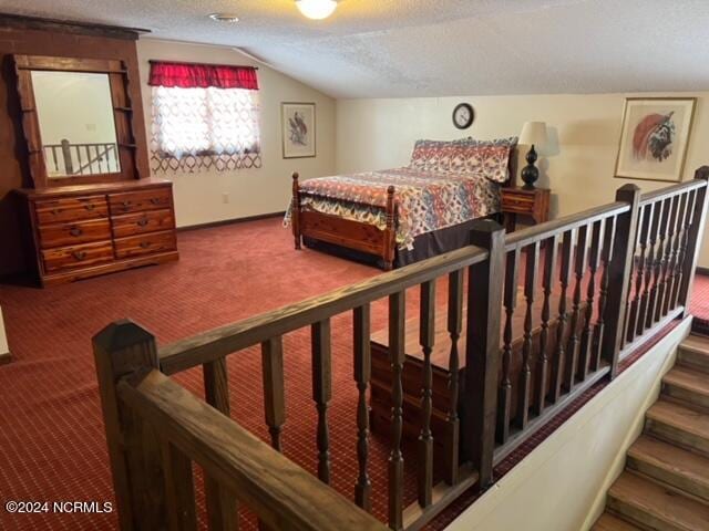 carpeted bedroom with vaulted ceiling and a textured ceiling