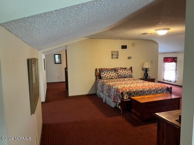 bedroom featuring a textured ceiling and dark colored carpet