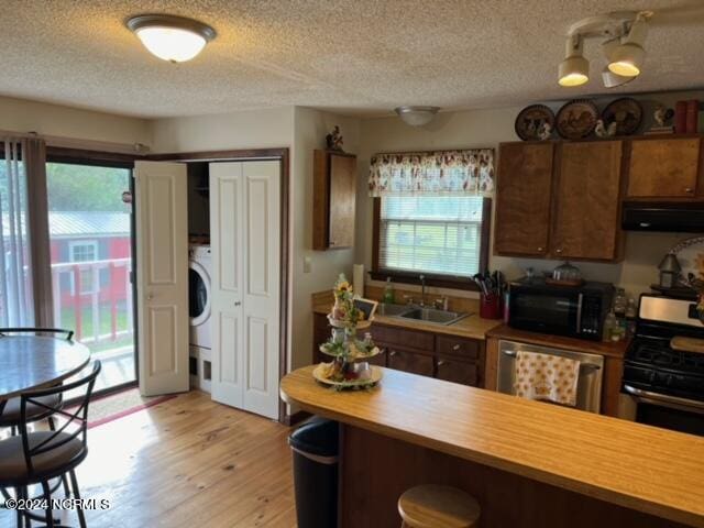 kitchen featuring exhaust hood, sink, stainless steel dishwasher, range with electric stovetop, and light hardwood / wood-style flooring