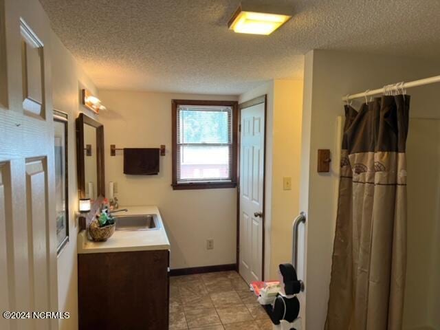 bathroom featuring a textured ceiling, vanity, and tile flooring