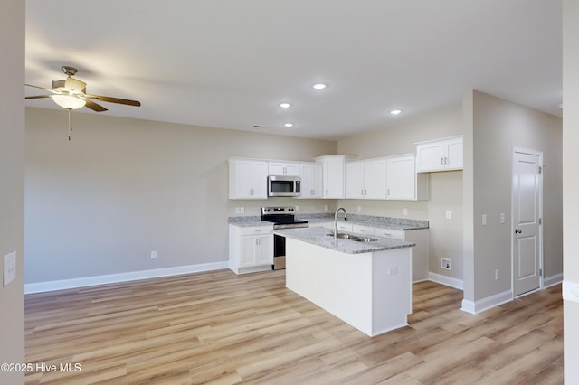 kitchen featuring sink, stainless steel appliances, light stone counters, an island with sink, and white cabinets