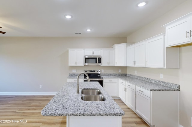 kitchen featuring white cabinets, sink, stainless steel appliances, and an island with sink