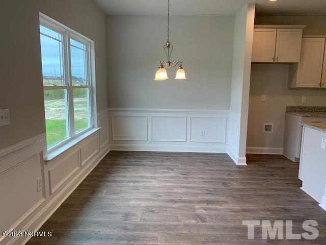 unfurnished dining area with dark wood-type flooring and a chandelier