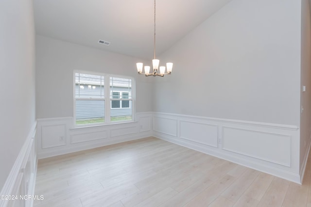 unfurnished room featuring vaulted ceiling, a notable chandelier, and light hardwood / wood-style floors