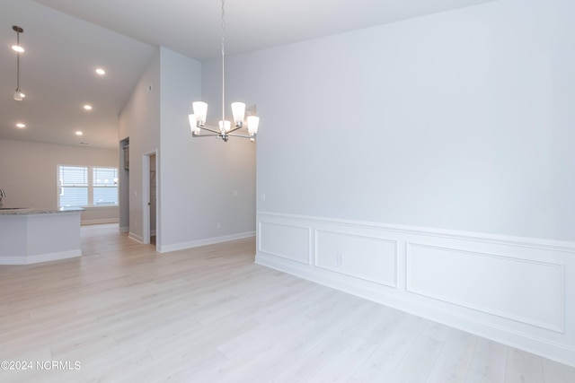 empty room featuring sink, light hardwood / wood-style floors, and a notable chandelier