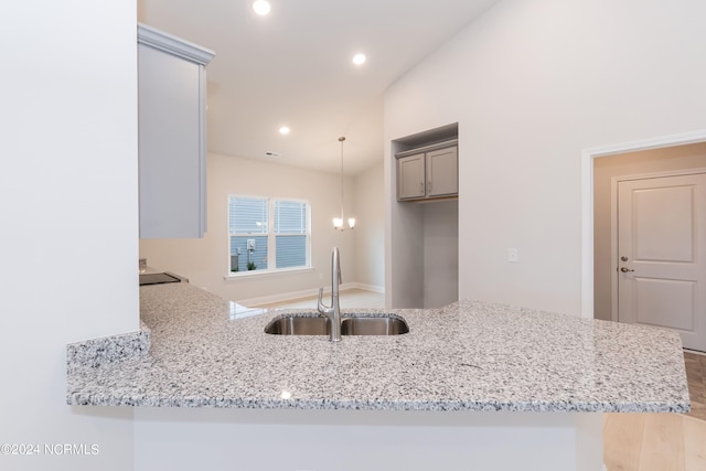 kitchen with decorative light fixtures, sink, gray cabinetry, and kitchen peninsula