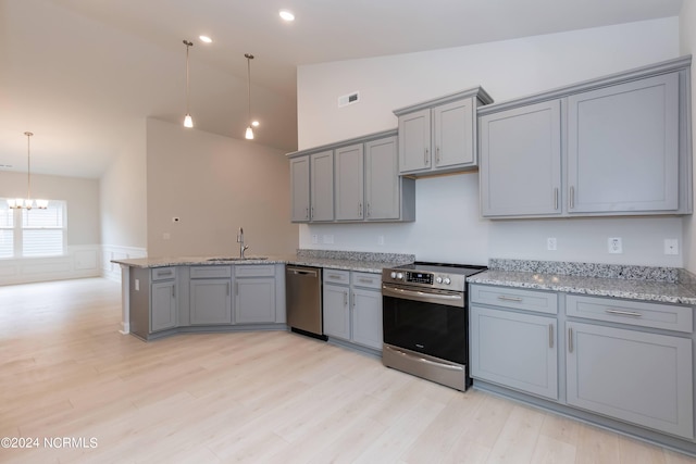 kitchen with gray cabinetry, stainless steel appliances, pendant lighting, and vaulted ceiling