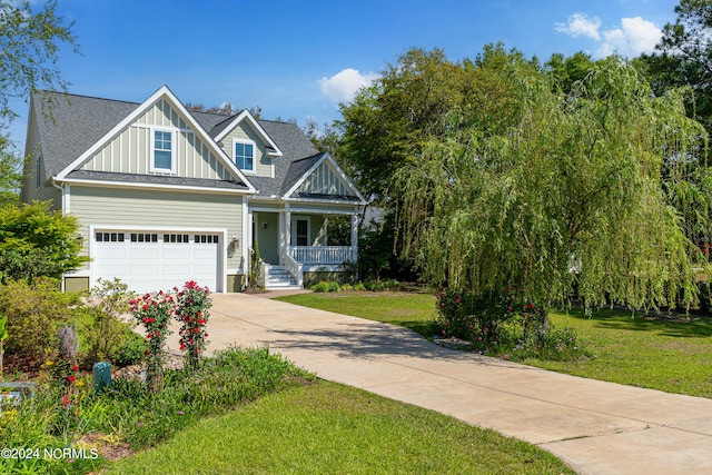 view of front of property featuring a garage, a porch, and a front yard