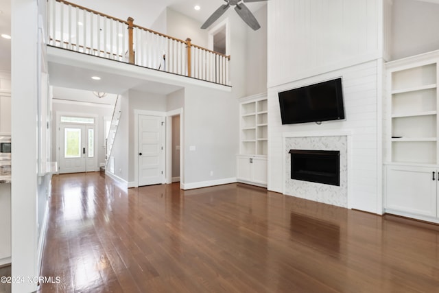 unfurnished living room with ceiling fan, dark hardwood / wood-style floors, and a high ceiling