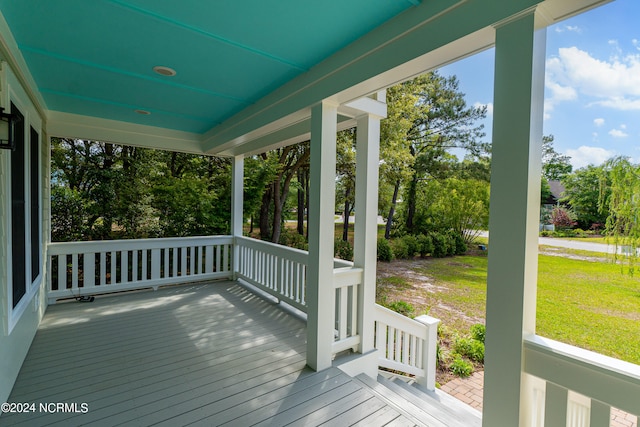 wooden deck with covered porch and a lawn