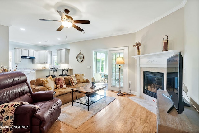 living room with a wealth of natural light, crown molding, ceiling fan, and light wood-type flooring