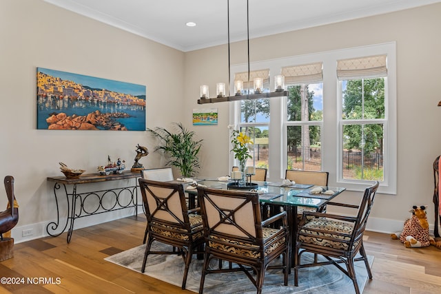 dining room featuring a chandelier, light wood-type flooring, and ornamental molding