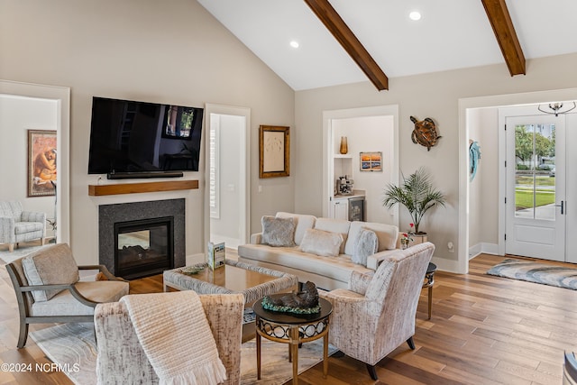 living room featuring vaulted ceiling with beams and light hardwood / wood-style flooring