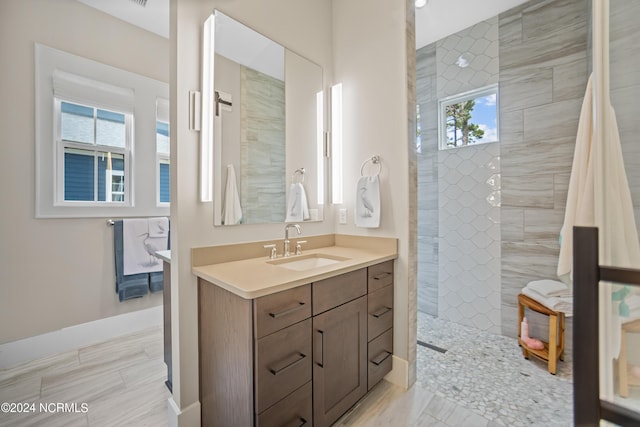 bathroom featuring tiled shower and vanity