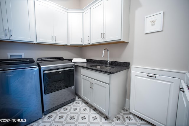 laundry area featuring sink, washing machine and clothes dryer, and cabinets