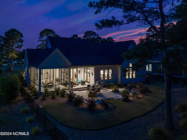 back house at dusk featuring a patio area