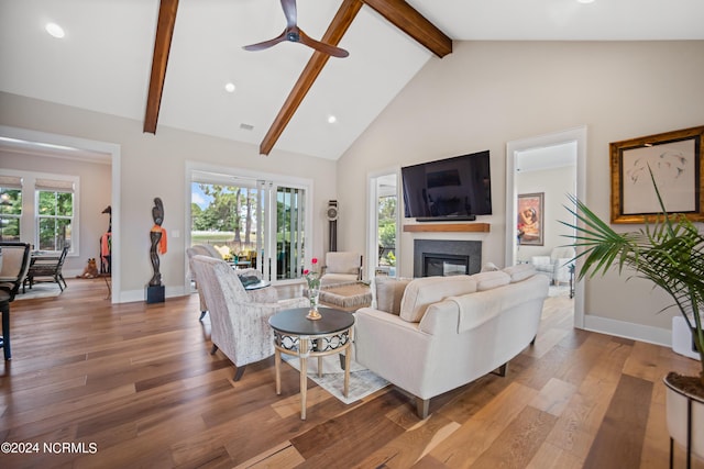 living room with ceiling fan, wood-type flooring, plenty of natural light, and beamed ceiling