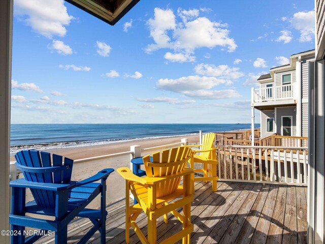 wooden terrace featuring a beach view and a water view