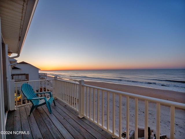 deck at dusk with a beach view and a water view