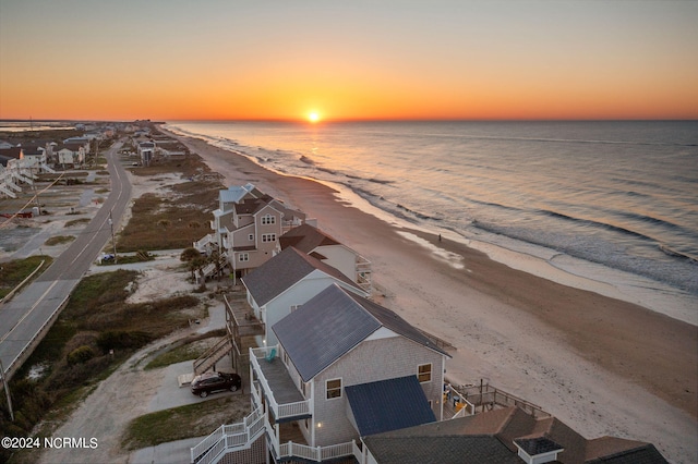 aerial view at dusk featuring a water view, a residential view, and a view of the beach