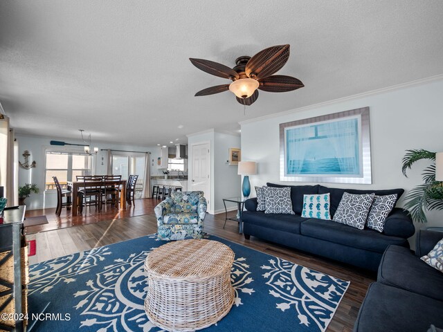 living room featuring ceiling fan with notable chandelier, ornamental molding, a textured ceiling, and dark hardwood / wood-style flooring