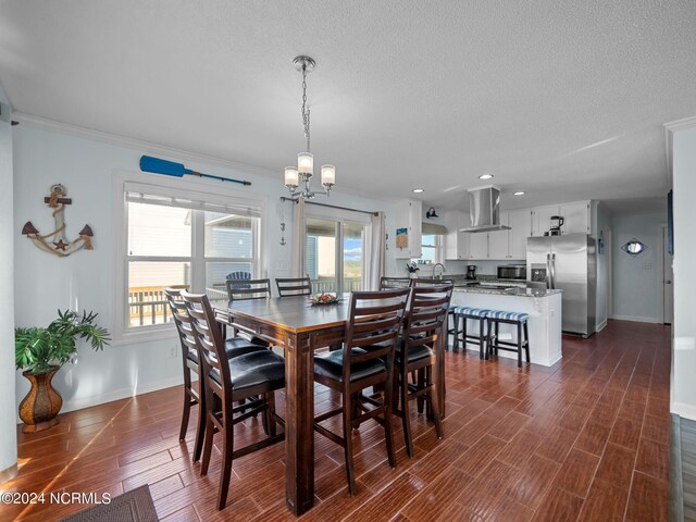 dining area featuring a wealth of natural light, a textured ceiling, an inviting chandelier, and ornamental molding