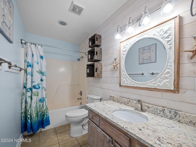 full bathroom with vanity, tile patterned floors, wooden walls, shower / bath combination with curtain, and toilet