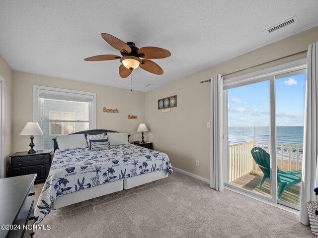 carpeted bedroom featuring ceiling fan, a textured ceiling, access to exterior, and a water view