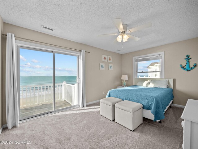 carpeted bedroom featuring a textured ceiling, ceiling fan, a water view, and access to outside