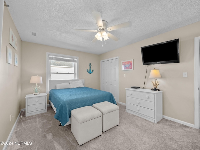 carpeted bedroom featuring ceiling fan, a closet, and a textured ceiling