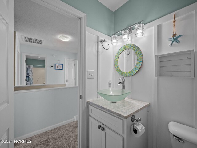 bathroom with a textured ceiling, toilet, and vanity