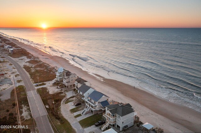 aerial view at dusk featuring a water view and a view of the beach