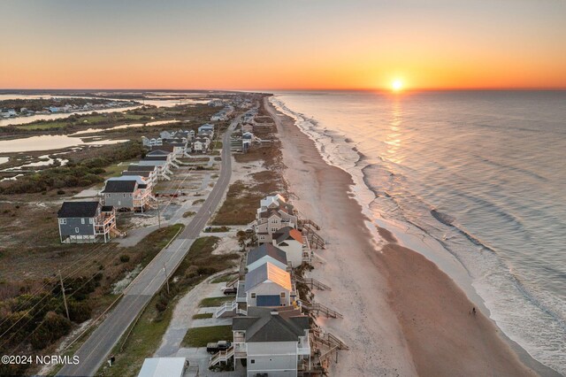 aerial view at dusk with a beach view and a water view